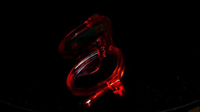 Modern orange transparent glasses rotating 360 degrees on a black background Stylish fashion optical frames 4k Video