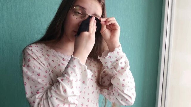 Teen girl polishing eyeglasses at home, vision care routine, personal maintenance and lifestyle concept.