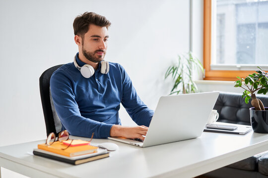Young programmer working on laptop at home office desk