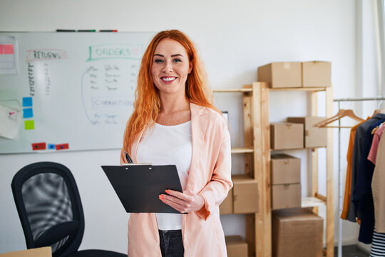 Young woman managing online clothing store orders in warehouse