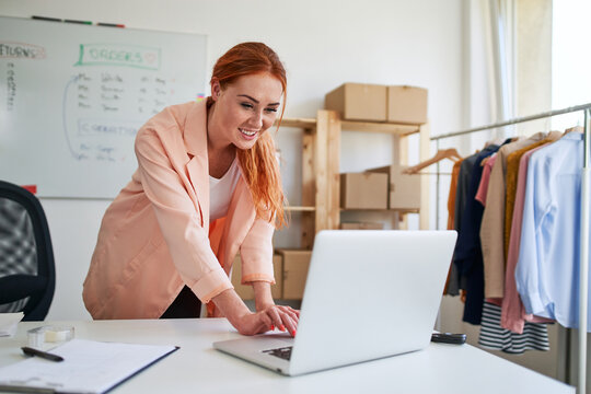 Young woman managing online clothing store orders on laptop