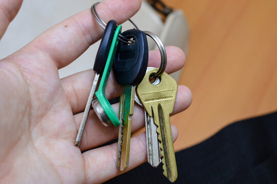 Hand holding bunch of keys with keychain, close up. Home access, security, property ownership, car keys, lock system and everyday object concept.