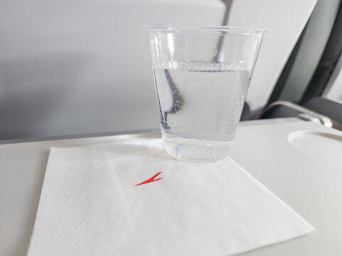 April 13, 2026, Brussels, Belgium. In flight. Plastic cup of water on Austrian Airlines tray table