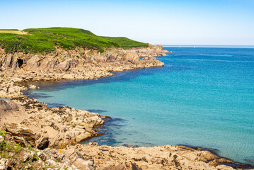 Obraz premium View of Pointe de Kermorvan from Blancs Sablons beach Le Conquet Finistere Brittany France showing rocky coast, turquoise sea, green headland and clear summer sky