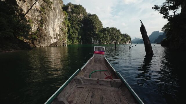 Cinematic POV from Traditional Wooden Longtail Boat Navigating Through Emerald Water and Ancient Dead Trees, Limestone Cliffs of Cheow Lan Lake, Khao Sok, 4k Stock Video