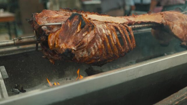 Whole pig roasting on a spit at a festival in the summer season