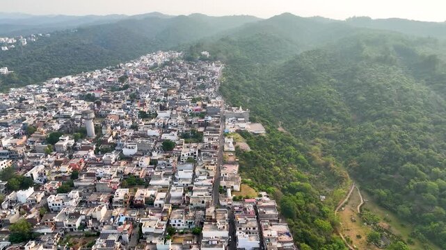 Circling shot of an overpopulated city bordering fragile forest ecosystem. This Shot clearly illustrates the ongoing environmental conflict of overpopulation, deforestration & rapid city expansion