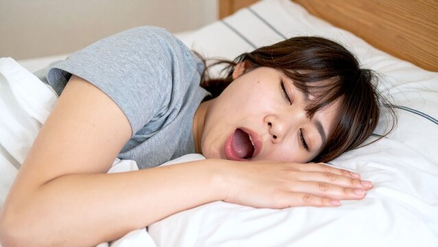 口を開けて布団で爆睡する20代の日本人女性