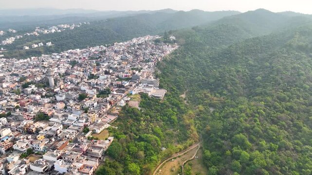 Lateral aerial view of dense housing encroaching on a green ridge.