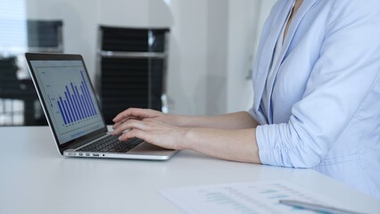 Fototapeta premium Business professional typing on a laptop computer, managing daily workflow and corporate tasks, working diligently in a modern office environment for busy business operations