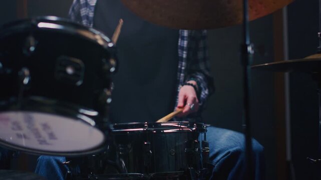 Young female drummer passionately playing a drum kit in a professional rehearsal studio, energetically striking cymbals and drums with drumsticks. Hair flying. Rock Feminist style. Woman power.