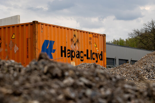 Orange hapag-lloyd shipping container standing on a gravel ground