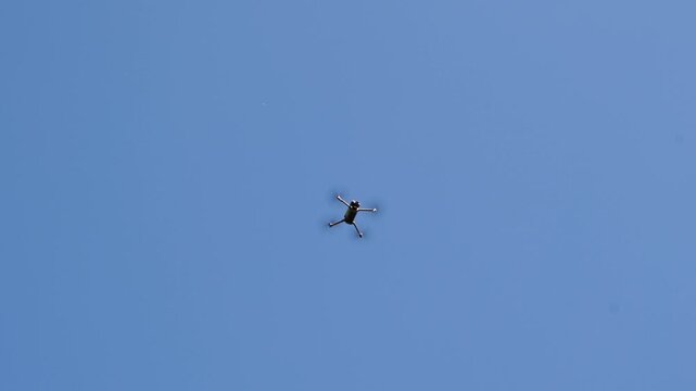 Drone soars calmly through vast open sky. Sky is clear, bright, and serene without clouds. Small aircraft glides smoothly, unobtrusive in view. Perfect for drone, aviation, or tech project visuals