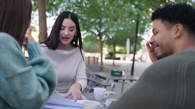 Diverse university students collaborating on a project. Young people learning and discussing ideas together while sitting at a table outdoors
