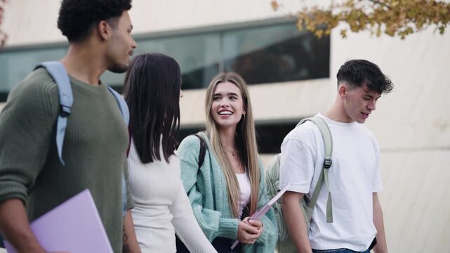 Diverse group of young students having a friendly conversation while walking together on the university campus after their classes