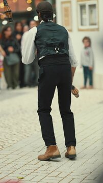 Man performs with batons in a street during a local festival event with spectators watching in a lively atmosphere