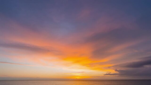 Vibrant sunset over a tranquil ocean horizon with streaks of orange, pink, and purple in the sky