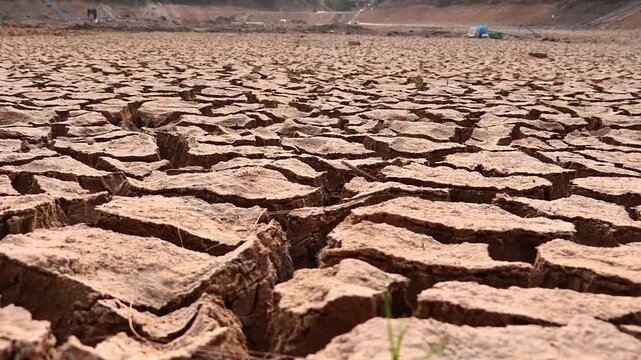 A cracked, barren earth surface, the ground dried and damaged due to a lack of water
