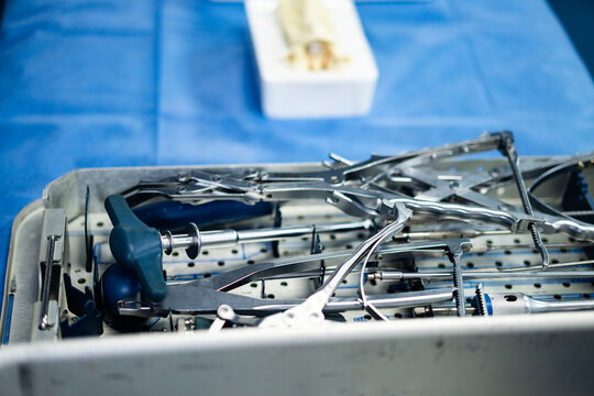 Orthopedic surgical instruments in a metal medical tray. Metal surgical tray filled with stainless steel orthopedic tools used for spinal surgery in a clinical setting.