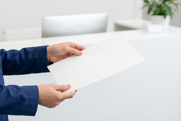 Obraz premium Two hands holding a blank white document in a clean office environment