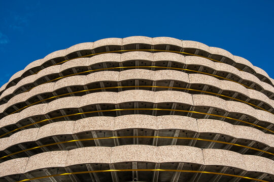 A curved facade of balconies forms a layered pattern on a building in Lyon, France, where urban architecture arcs beneath clear sky