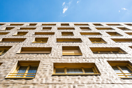 A textured facade in Lyon, France, turns windows into a repeated pattern as urban architecture and building edges climb toward open sky