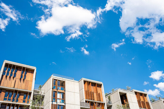 A residential facade lifts architecture in Lyon, France, toward blue sky and cloud, where wood accents and windows shape an urban edge