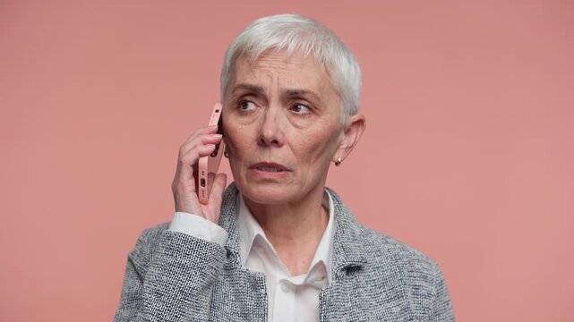 Senior Woman Having Serious Phone Call on Pink Background