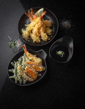 Flat lay view of crispy tempura with dipping sauce on a table.
