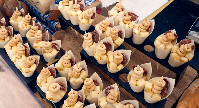 Traditional Italian appetizers in paper cones displayed during Aromatica festival. Local street food snacks contain cheese cubes salami and taralli crackers for tasting during annual gastronomic event
