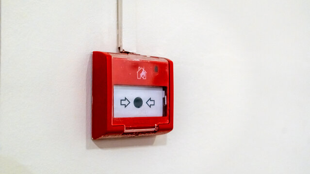Red fire alarm box mounted on white wall