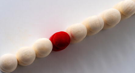 Single red bead stands out among creamy wooden beads © I