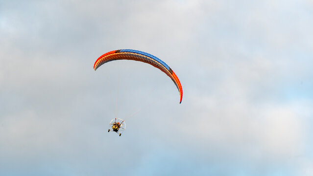 Paraglider soars above soft, cloudy sky