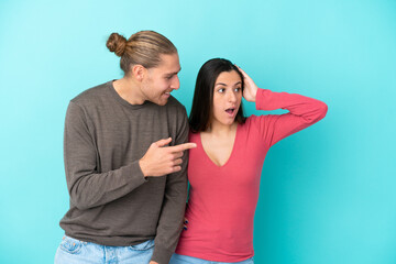 Obraz premium Young caucasian couple isolated on blue background pointing finger to the side with a surprised face