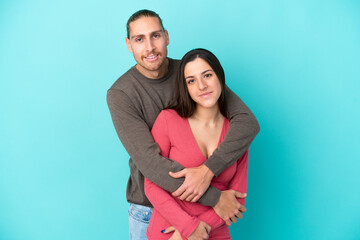 Fototapeta premium Young caucasian couple isolated on blue background hugging