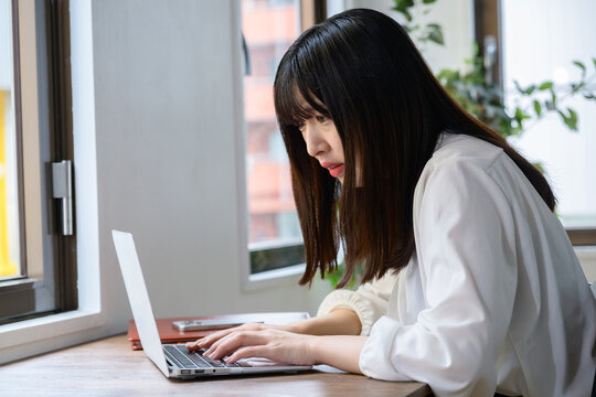 オフィスでノートパソコンを見て悩む日本人女性