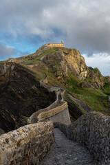 Fototapeta premium Stone pathway leading to San Juan de Gaztelugatxe under dramatic sky