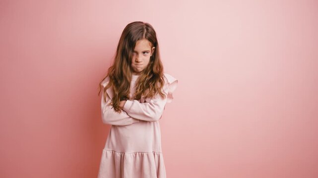 Young girl crossing her arms and feeling grumpy. Unhappy female child showing anger and disapproval, making silly faces at the camera