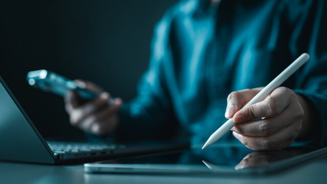 Business professional using tablet and smartphone for financial analysis, digital auditing and data management in a modern office workspace environment.