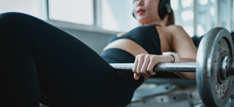 Woman performing barbell hip thrust in modern gym, building lower body strength and fitness. Healthy lifestyle, workout motivation, active training routine and wellness concept.