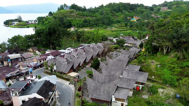 Drone aerial of Batak traditional architecture and green hillside in Samosir Lake Toba