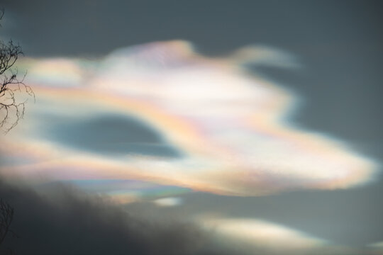 Rare iridescent nacreous cloud glowing in a pastel Arctic twilight sky above dark clouds, soft atmospheric winter scene in Norway