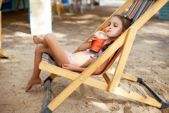 A little girl on the beach with a cocktail in her hands. Vacation.