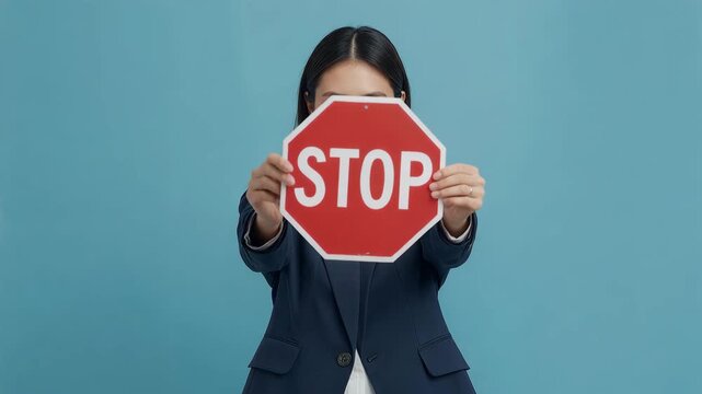 青い背景でSTOPサインを掲げ注意を促す日本人女性