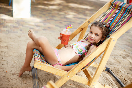 A little girl on the beach with a cocktail in her hands. Vacation.