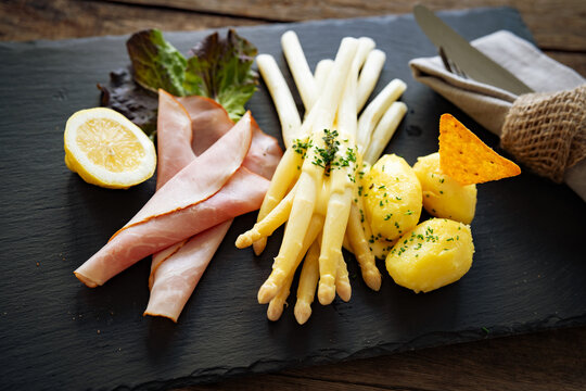 Seasonal white asparagus with creamy hollandaise sauce, served on a slate plate. Decoration suggestion for a modern seasonal cuisine.
