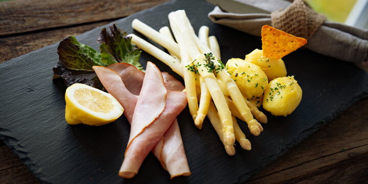 Seasonal white asparagus with creamy hollandaise sauce, served on a slate plate. Decoration suggestion for a modern seasonal cuisine.