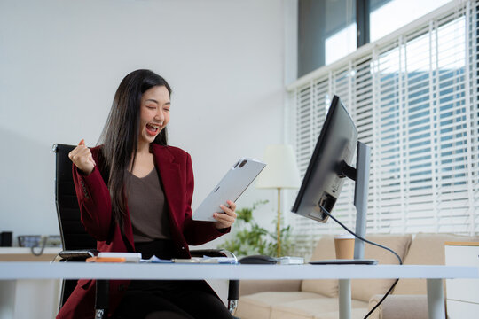 Overjoyed, Asian female businessman celebrates a financial bonus.