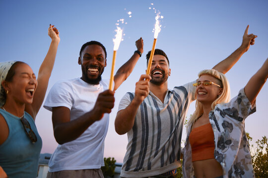 Young friends celebrating together with sparklers during rooftop gathering