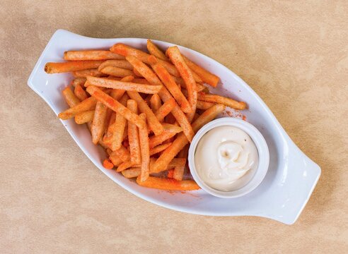 Seasoned french fries with creamy cheese dip served on white platter
